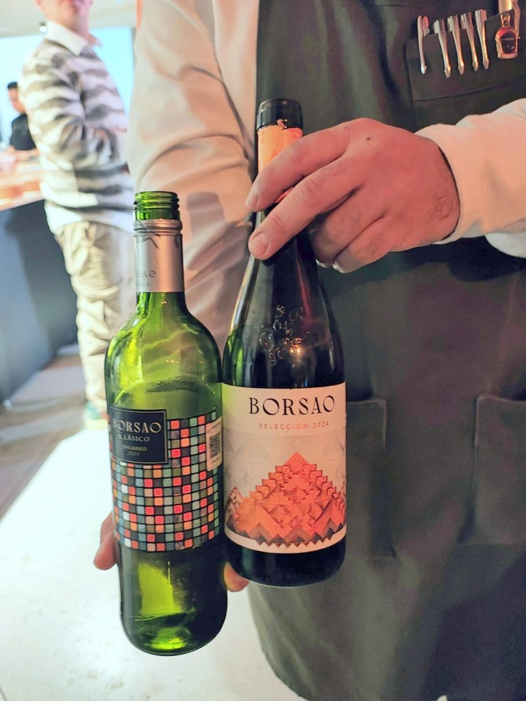 Dos botellas de vino Borsao, una blanca y una tinto, en manos de un camarero.