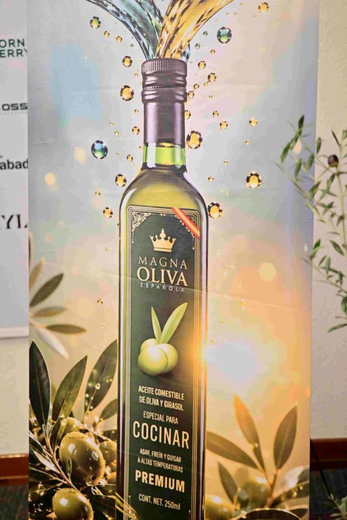 Botella de aceite comestible de oliva y girasol Magna Oliva, destacando su uso para cocinar a altas temperaturas. Fondo con gotas de aceite y hojas de olivo.